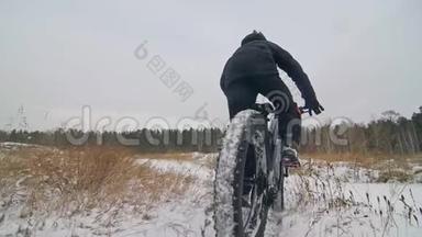 专业的极限运动运动员骑胖自行车在户外。 骑自行车在冬天的雪田，森林。 人类