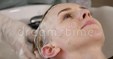 现代水疗中心的头发护理。 在发廊的理发师洗头发的女人。 女人在水疗中心洗头。 水疗中心