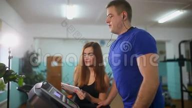 男子在跑步机上运动女孩在跑步机教练，运动健康的生活方式