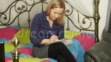 漂亮的女人在她房间里的一张床上<strong>学习笔记</strong>本电脑。 网上教育