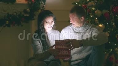 年轻夫妇在新年装饰和礼物和圣诞树上相爱，视频里有噪音
