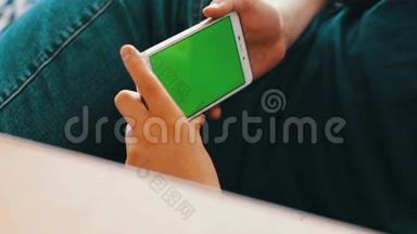 手持触摸屏设备，使用智能手机特写青少年手。 彩色钥匙，绿色屏幕