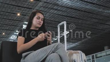 年轻漂亮的女商人在机场使用智能手机，等待排队登记，旅行概念
