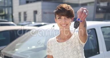 年轻女子拿着新车的钥匙对着镜头微笑