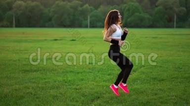 日落时分，在草地上一个<strong>运动</strong>的女孩，穿着白色的上衣和粉<strong>红色</strong>的<strong>运动</strong>鞋，在提起前进行热身<strong>运动</strong>