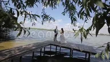 一对年轻漂亮的新婚夫妇站在湖边。 结婚纪念日。 慢动作