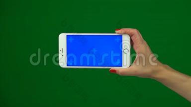 手拿着蓝色屏幕智能手机在绿色屏幕上