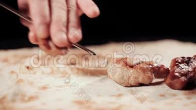 把食物夹起来。 手从扦子中取出什什串。 把什什烤肉串放在皮塔面包上。 什什烤肉串。 黑色背景。