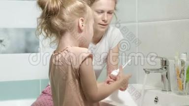 妈妈轻轻地刷牙她心爱的女儿的牙齿一个小女孩和她的母亲轻轻地清洁牙齿后，吃。