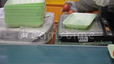 工人用塑料绿色托盘包装西红柿，她的工作场所特写。