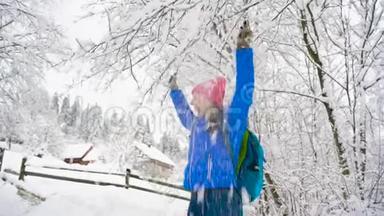 女人在玩-她在摇动树枝，雪落在她身上。 <strong>晴朗晴朗</strong>的霜冻天气