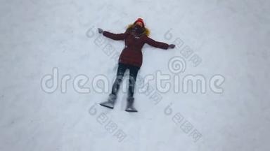 一个年轻的女孩在阳光明媚的冬日做一个雪天使。 慢动作。 4K.