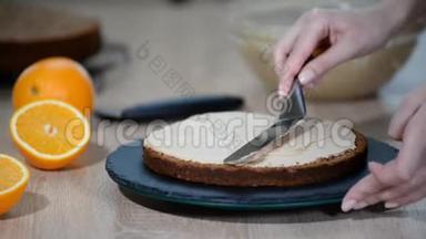 糖果师把奶油放在蛋糕的顶部。 面包师平滑蛋糕与奶油糖霜。