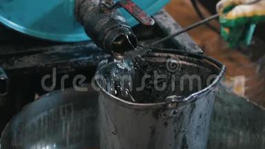 工人把发动机油或化学液体倒入旧的刮水桶中
