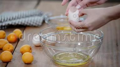 女人的手打破一个鸡蛋，以分离蛋清和蛋黄和鸡蛋壳的背景。