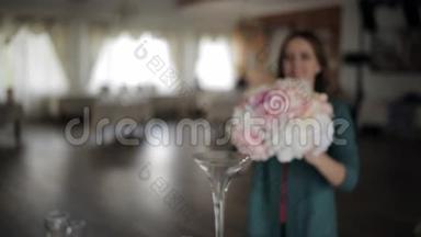 年轻女子在餐桌上装饰鲜花，在高玻璃花瓶中装饰鲜花，节日餐桌装饰，婚礼