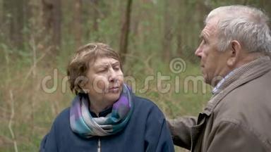 一对年老美丽的夫妇坐在木头上，坐在锯木上。 他们温柔地交谈，拥抱，相爱地互相看着