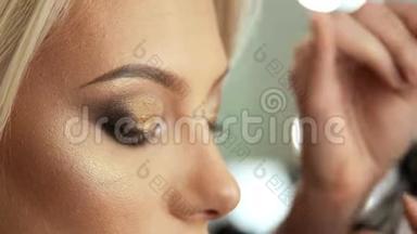 美容沙龙化妆师将睫毛贴在金色眼睛上