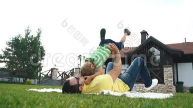 父亲和他的小儿子在夏天公园的草地上玩耍。