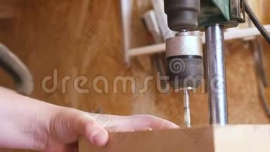 工人在木模板上钻洞。 木制玩具的制造。 特写双手。