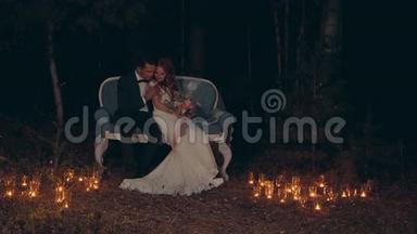 新婚夫妇在夜晚<strong>拥</strong>抱和亲吻，<strong>坐</strong>在黑暗的森林里的沙发上。