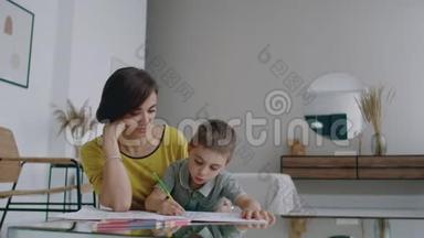 美丽的年轻母亲穿着一件暖和的毛衣躺在地板上，我的儿子在纸上<strong>画</strong>着记号，描绘着他的<strong>形象</strong>