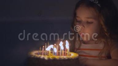 小美丽的女孩正在缓慢地在生日蛋糕上吹九支蜡烛