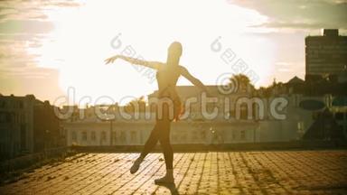 年轻优雅的女芭蕾舞演员在屋顶上跳舞-日落
