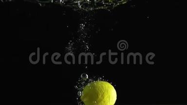 柠檬落入水中，在黑色背景下拍摄
