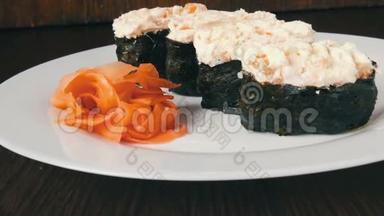 一个白色的<strong>大盘</strong>子，上面放着四个巨大的寿司黑吉里，旁边是粉红色的生姜和绿色的芥末
