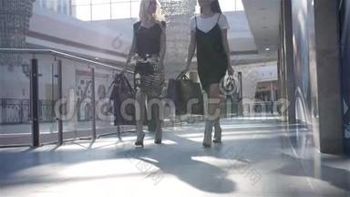 两个正在<strong>购物</strong>的女朋友站在自动扶梯上，手里拿着袋子，<strong>时尚</strong>女<strong>购物</strong>