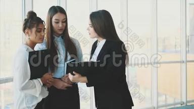 集团友好的三个多民族商人站在办公大厅，拿着文件，学习<strong>财务报告</strong>。