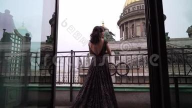 年轻的黑发女人，穿着黑色豪华礼服，住在城市的阳台上