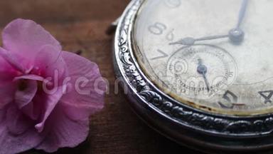 在一朵浅粉色紫罗兰花旁边的怀表特写和时间的流逝