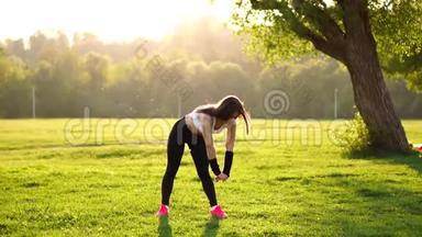 穿着白色<strong>上衣</strong>、黑色<strong>紧身</strong>裤和粉色运动鞋的运动型黑发女郎在阳光下伸展肌肉，准备