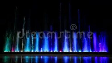 舞动着美丽的彩色喷泉，倒影在冰中。 宽低角度拍摄..