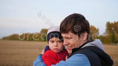 一个年轻的父亲把他的孩子抱在怀里。 温柔和怀抱的挚爱父亲.. 户外活动
