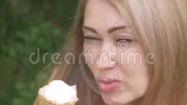 女人舔冰淇淋。 女孩在舔一个美味的奶油冰淇淋。 有草莓味的冰淇淋甜筒