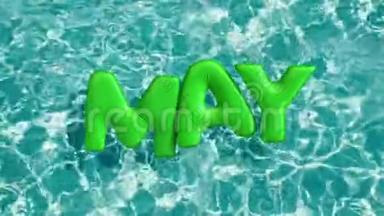 单词`5月`形状的充气游泳圈漂浮在清爽的蓝色游泳池