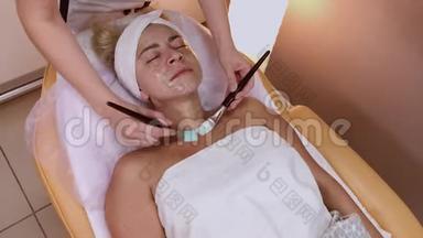 <strong>专业美容师</strong>在女人脸上涂上刷子的面膜。