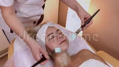 <strong>专业美容师</strong>在女人脸上涂上刷子的面膜。