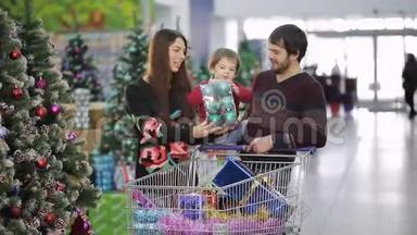 在超市里购物。 一个年轻的家庭正在超市购物过圣诞节.. 母亲、父亲和儿子