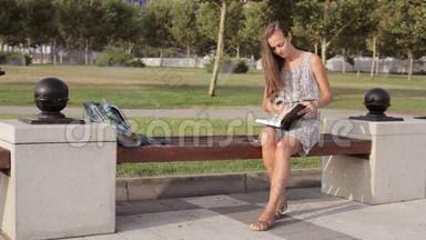 坐在长凳上拿书的年轻女子