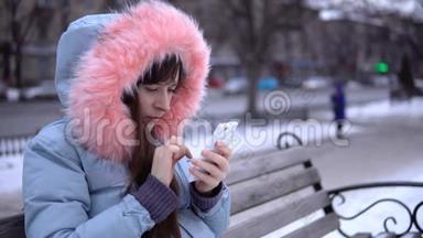 冬天，一个穿着灰色保暖夹克的年轻女人在街上用电话。