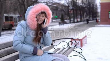 <strong>冬天</strong>，一个穿着灰色<strong>保暖</strong>夹克的年轻女人在街上用电话。