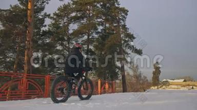 专业的极限运动运动员骑胖自行车在户外。 骑自行车在冬天的雪田，森林。 人类