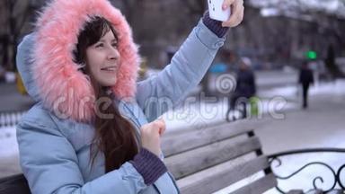 冬天，一个穿着灰色保暖夹克的年轻女人在街上用电话。