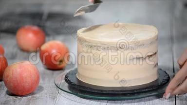 厨师用奶油装饰一个美味的蛋糕。 做焦糖苹果蛋糕。