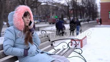 <strong>冬天</strong>，一个穿着灰色<strong>保暖</strong>夹克的年轻女人在街上用电话。