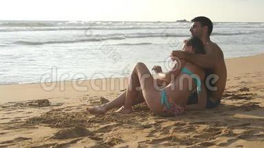 年轻的浪漫夫妇正<strong>坐</strong>在海滩上<strong>拥</strong>抱着美丽的景色。 一个女人和一个男人<strong>坐</strong>在一起